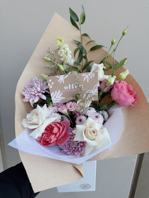 Bouquet of flowers with a visible brand card on a neutral background